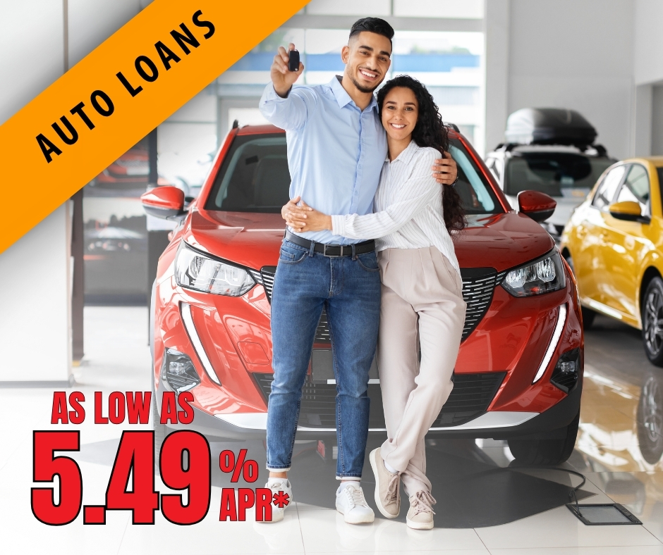 Young couple hugging in front of their new red automobile.